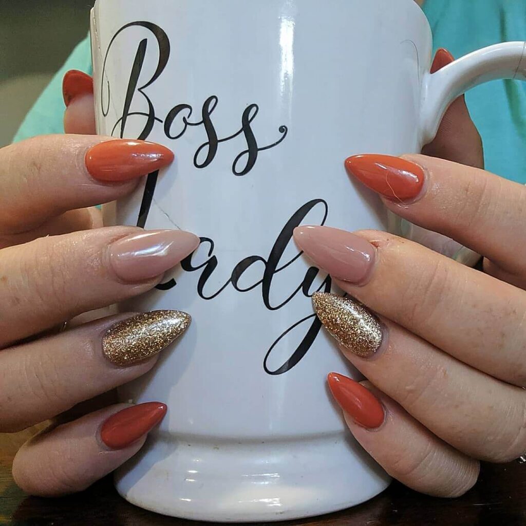 Close-up of warm-toned pumpkin spice nails with a fall-inspired design.