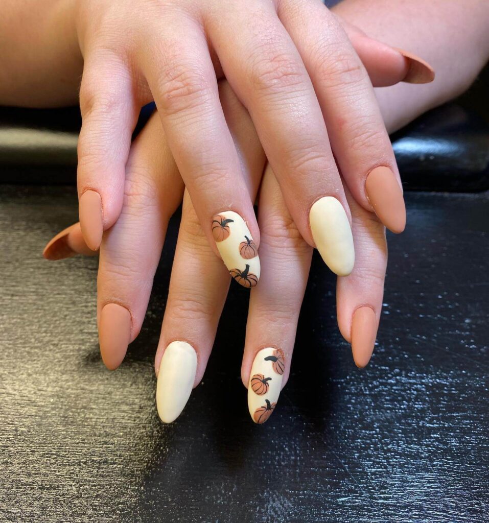 Close-up of warm-toned pumpkin spice nails with a fall-inspired design.