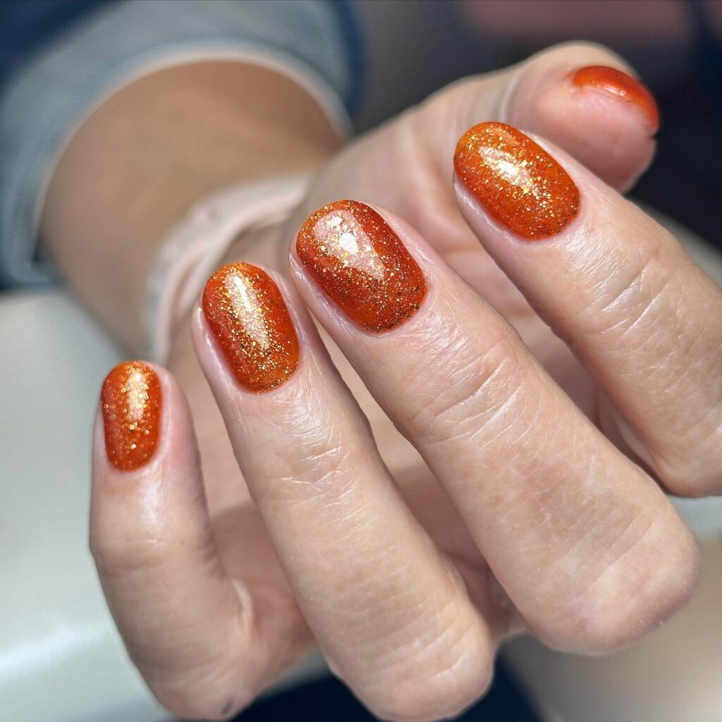 Close-up of warm-toned pumpkin spice nails with a fall-inspired design.