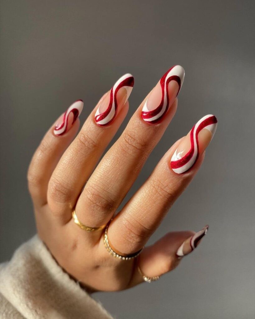 candy cane nails with red and white stripes and glitter accents, perfect for a festive holiday look.