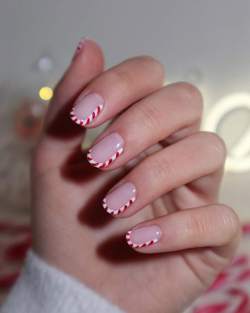 candy cane nails with red and white stripes and glitter accents, perfect for a festive holiday look.