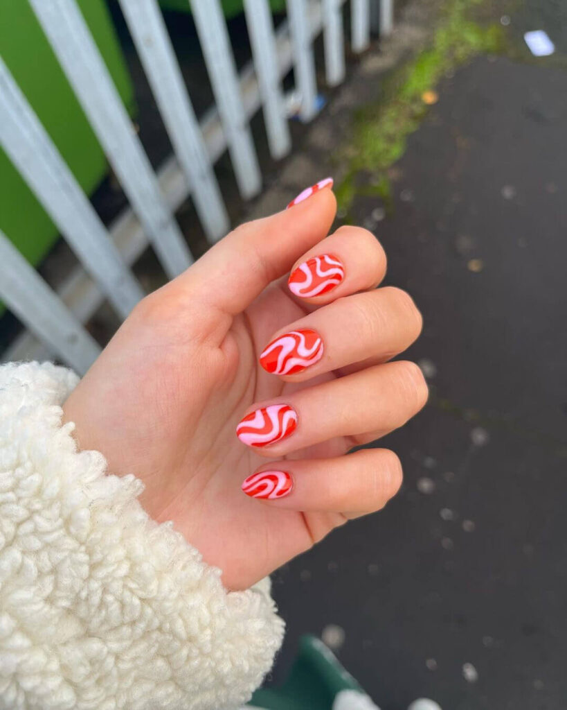 candy cane nails with red and white stripes and glitter accents, perfect for a festive holiday look.