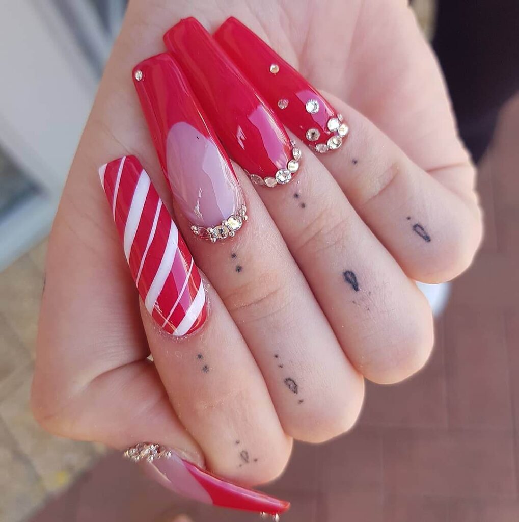 candy cane nails with red and white stripes and glitter accents, perfect for a festive holiday look.